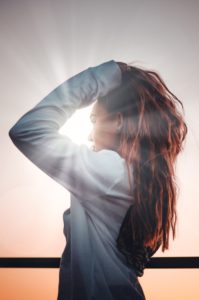 woman with back mostly to camera, looking into the sun